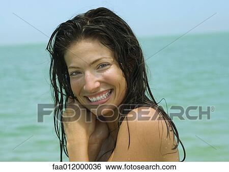 Woman with wet hair, smiling, sea in background View Large Photo Image Stock Photograph - Woman with wet hair, smiling, sea in background. Fotosearch