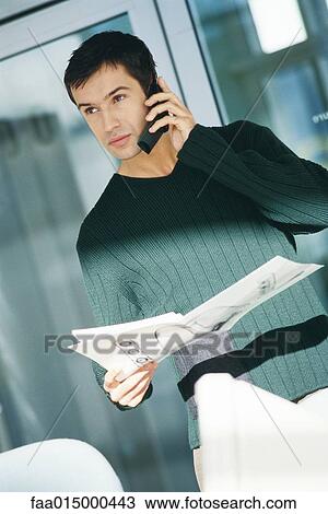 Young male office worker holding document, using telephone View Large Photo Image Stock Image - Young male office worker holding document, using telephone. Fotosearch