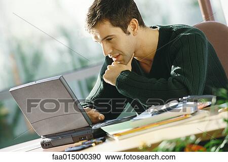 Young man using laptop View Large Photo Image Stock Image - Young man using laptop. Fotosearch