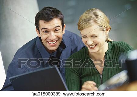 Stock Photo - Young woman and man with laptop, smiling. Fotosearch