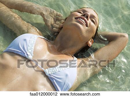 Young woman in bikini lying in shallow water on beach View Large Photo Image Stock Image - Young woman in bikini lying in shallow water on beach. Fotosearch