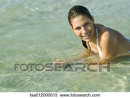 Young woman in bikini lying in shallow water on beach View Large Photo Image Stock Photography - Young woman in bikini lying in shallow water on beach. Fotosearch