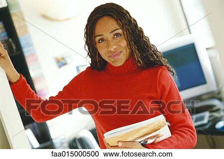 Young woman in office, smiling at camera View Large Photo Image Stock Image - Young woman in office, smiling at camera. Fotosearch