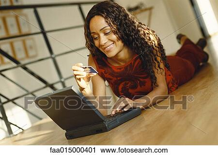 Young woman lying on ground with laptop, holding up credit card View Large Photo Image Stock Image - Young woman lying on ground with laptop, holding up credit card. Fotosearch