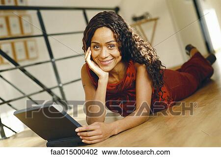 Young woman lying on ground with laptop, smiling at camera View Large Photo Image Stock Image - Young woman lying on ground with laptop, smiling at camera. Fotosearch