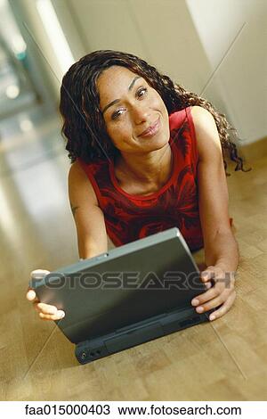 Young woman lying on ground with laptop, smiling at camera View Large Photo Image Stock Image - Young woman lying on ground with laptop, smiling at camera. Fotosearch