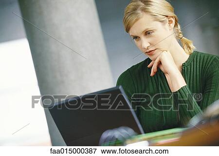 Young woman using laptop, hand under chin View Large Photo Image Stock Photo - Young woman using laptop, hand under chin. Fotosearch
