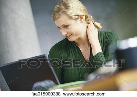Young woman using laptop, smiling, hand behind neck View Large Photo Image Stock Photo - Young woman using laptop, smiling, hand behind neck. Fotosearch
