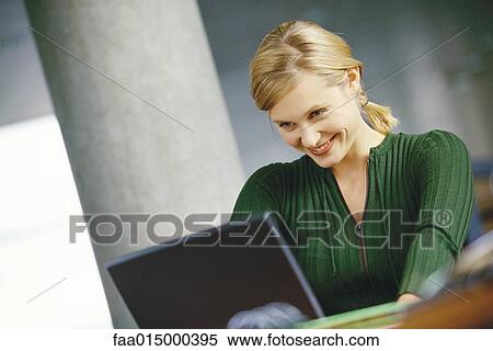 Stock Photography - Young woman using laptop, smiling. Fotosearch