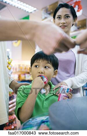 Boy eating sweet snack as father pays for it View Large Photo Image Stock Image - Boy eating sweet snack as father pays for it. Fotosearch