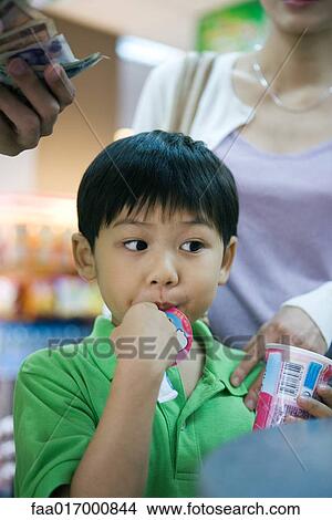 Boy eating sweet snack at checkout counter View Large Photo Image Picture - Boy eating sweet snack at checkout counter. Fotosearch