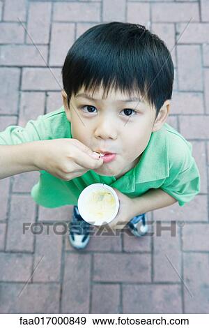 Boy eating sweet snack, smiling at camera View Large Photo Image Stock Photo - Boy eating sweet snack, smiling at camera. Fotosearch
