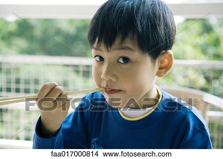 Picture - Boy eating with chopsticks. Fotosearch