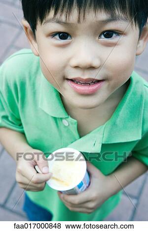 Stock Photo - Boy holding sweet snack, smiling at camera. Fotosearch
