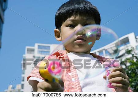 Boy making bubbles with bubble gun View Large Photo Image Stock Photograph - Boy making bubbles with bubble gun. Fotosearch
