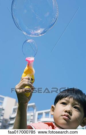 Stock Photography - Boy making bubbles with bubble gun. Fotosearch