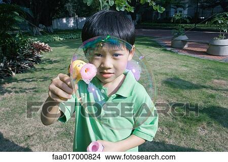 Picture - Boy making bubbles with bubble wand. Fotosearch