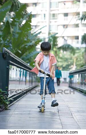 Boy playing on push scooter, full length View Large Photo Image Stock Photo - Boy playing on push scooter, full length. Fotosearch