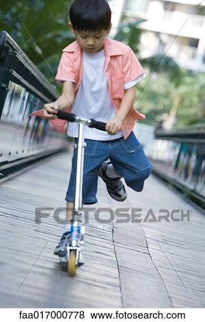 Boy playing on push scooter, full length View Large Photo Image Stock Photo - Boy playing on push scooter, full length. Fotosearch