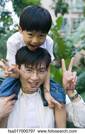 Stock Photo - Boy riding on father's shoulders, front view, smiling at camera. Fotosearch