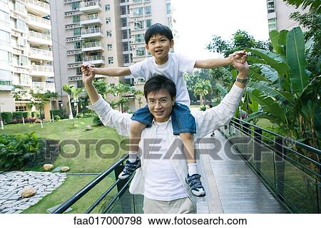 Boy riding on father's shoulders, front view, smiling at camera View Large Photo Image Stock Photo - Boy riding on father's shoulders, front view, smiling at camera. Fotosearch