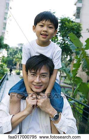 Stock Photography - Boy riding on father's shoulders, front view, smiling at camera. Fotosearch