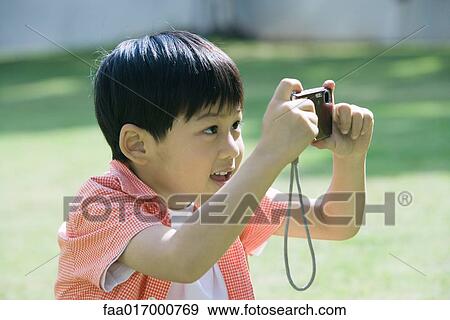 Stock Photo - Boy taking photo with digital camera. Fotosearch