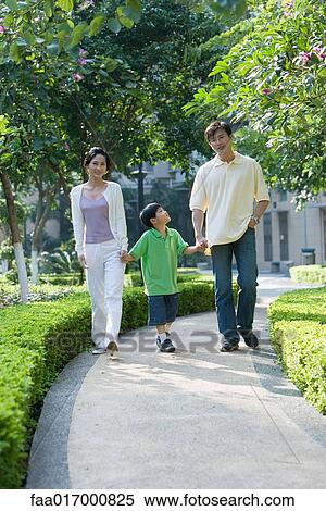 Boy walking hand in hand with parents, full length View Large Photo Image Stock Photography - Boy walking hand in hand with parents, full length. Fotosearch