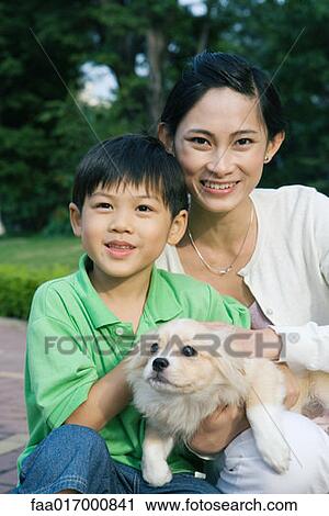 Stock Image - Boy with mother and pet dog, portrait. Fotosearch
