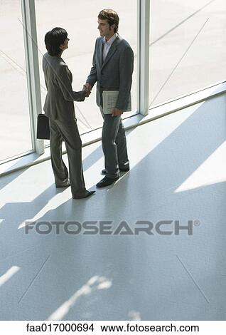 Business associates shaking hands, high angle view View Large Photo Image Picture - Business associates shaking hands, high angle view. Fotosearch