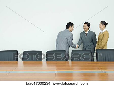 Picture - Business associates shaking hands in conference room. Fotosearch