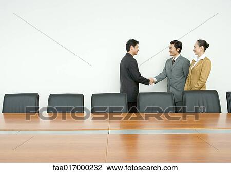 Stock Image - Business associates shaking hands in conference room. Fotosearch