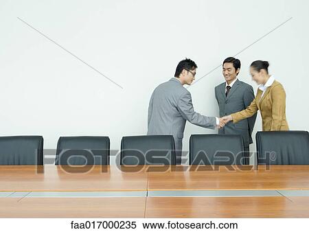 Stock Photography - Business associates shaking hands in conference room. Fotosearch