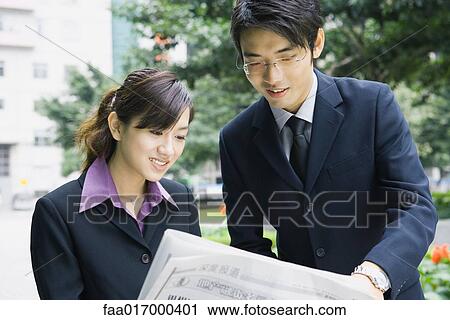 Stock Image - Business couple reading newspaper. Fotosearch