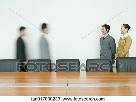 Business executives standing, facing associates arriving in conference room View Large Photo Image Stock Image - Business executives standing, facing associates arriving in conference room. Fotosearch