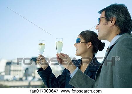 Business partners holding up glasses of champagne, skyline in background View Large Photo Image Stock Photo - Business partners holding up glasses of champagne, skyline in background. Fotosearch