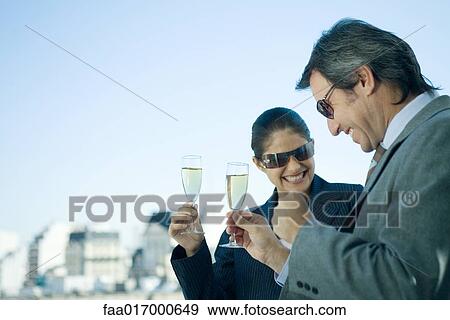 Business partners holding up glasses of champagne, skyline in background View Large Photo Image Stock Photo - Business partners holding up glasses of champagne, skyline in background. Fotosearch