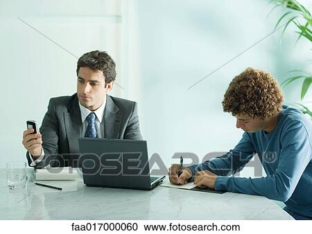 Stock Photography - Businessman and intern sitting at table. Fotosearch - Search Stock Photos, Pictures, Wall Murals, Images, and Photo Clipart
