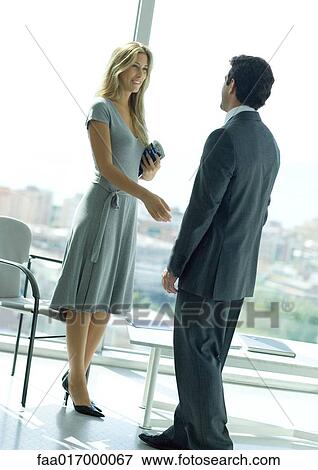 Stock Photo - Businessman and woman shaking hands in lobby. Fotosearch
