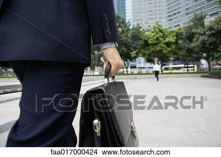 Picture - Businessman carrying briefcase, mid section. Fotosearch