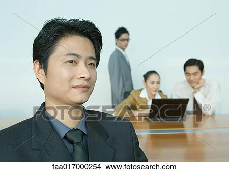 Picture - Businessman, colleagues working in background, portrait. Fotosearch