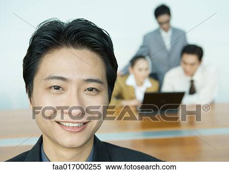 Stock Photography - Businessman, colleagues working in background, portrait. Fotosearch