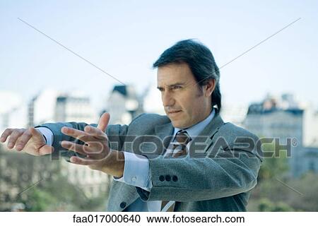 Businessman holding arms out in front of him and pointing, looking out of frame View Large Photo Image Stock Image - Businessman holding arms out in front of him and pointing, looking out of frame. Fotosearch