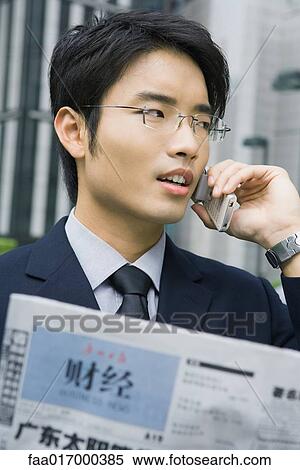 Businessman holding Chinese newspaper, using cell phone View Large Photo Image Stock Photography - Businessman holding Chinese newspaper, using cell phone. Fotosearch