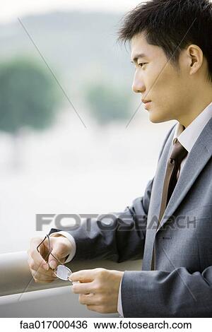 Stock Photograph - Businessman holding glasses, side view. Fotosearch