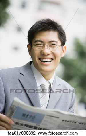 Stock Image - Businessman holding newspaper, laughing. Fotosearch