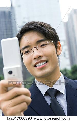 Businessman holding up cell phone, smiling View Large Photo Image Stock Image - Businessman holding up cell phone, smiling. Fotosearch