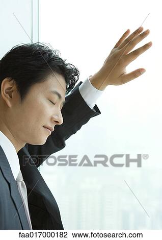 Businessman leaning against window of high rise, eyes shut View Large Photo Image Stock Image - Businessman leaning against window of high rise, eyes shut. Fotosearch