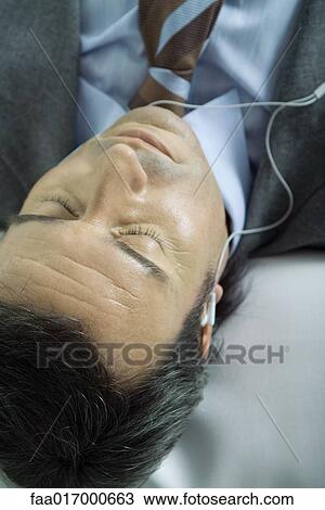 Businessman listening to earphones, eyes closed View Large Photo Image Stock Image - Businessman listening to earphones, eyes closed. Fotosearch
