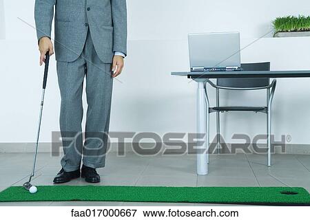 Businessman putting on artificial turf in office View Large Photo Image Stock Photo - Businessman putting on artificial turf in office. Fotosearch